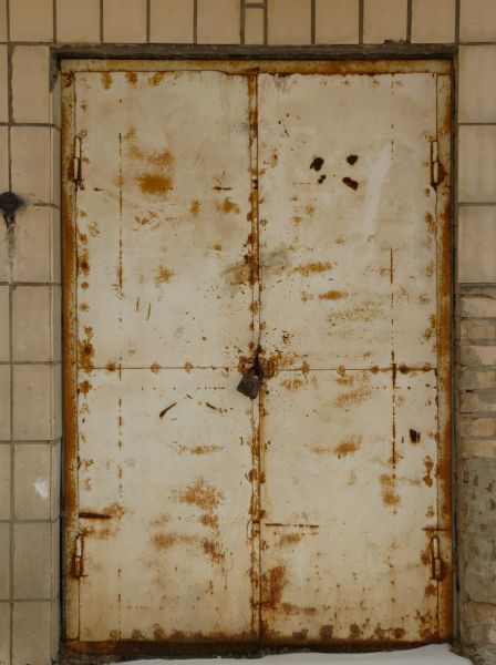 Very old beige doors with padlock and myriads of rust spots.